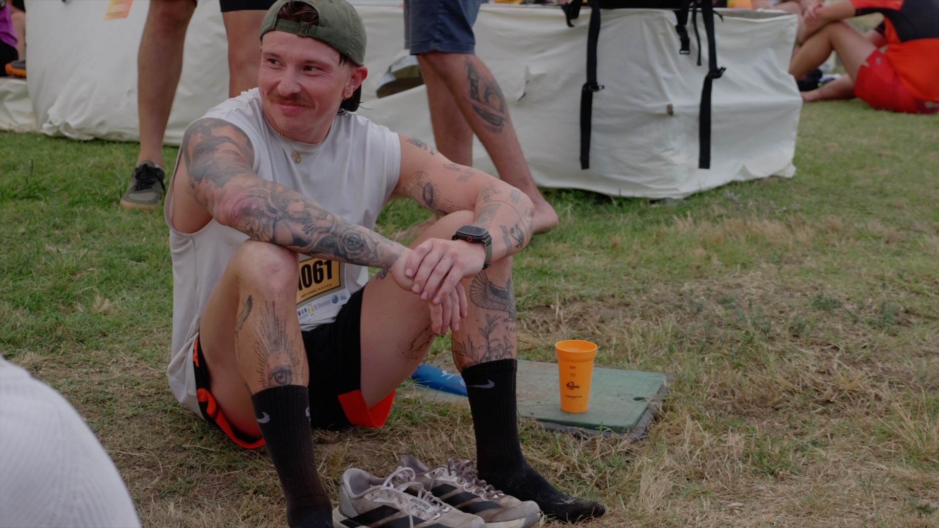 Coureur tatoué au repos dans l'herbe après le trail