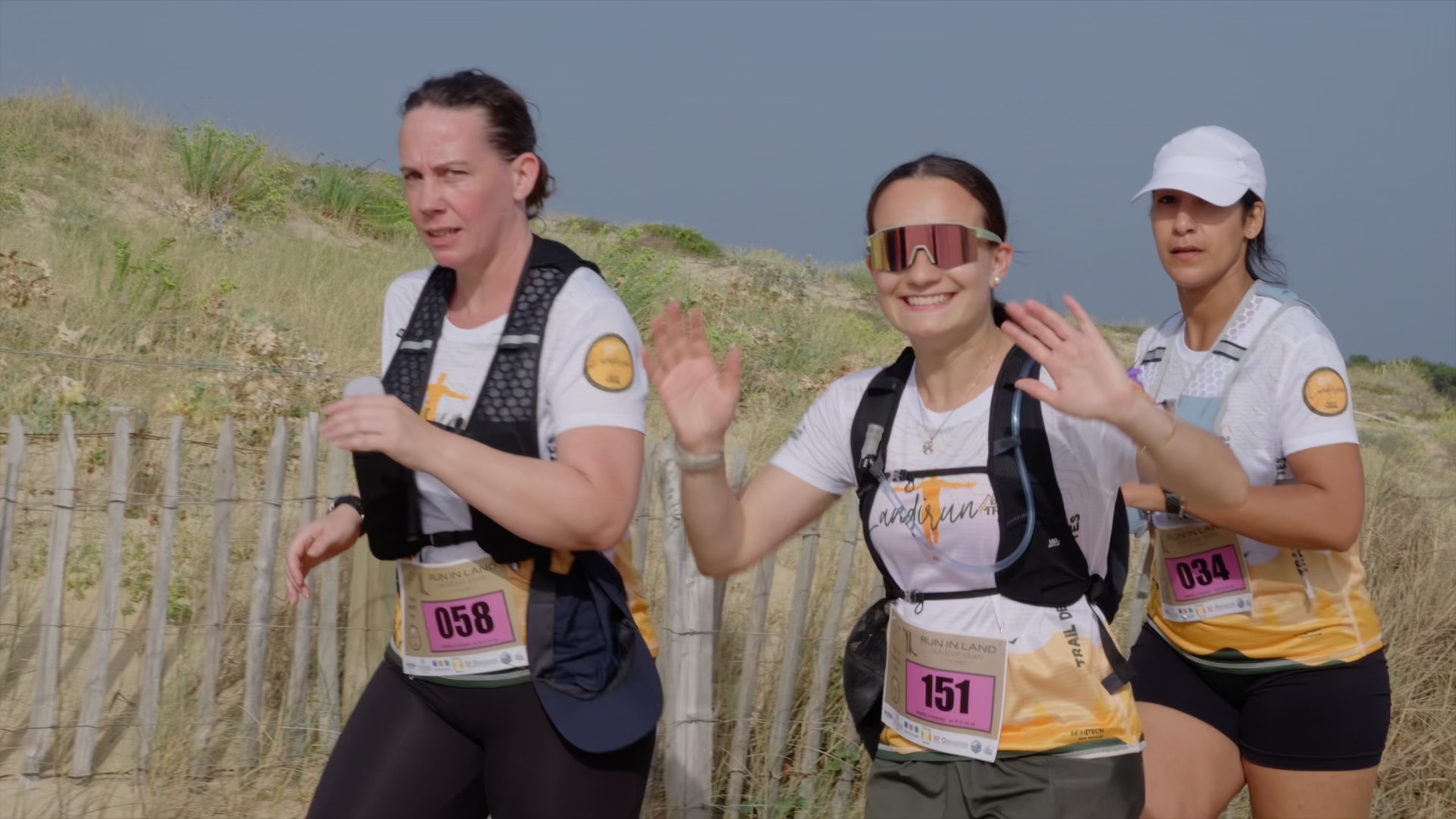 Trois coureuses saluent sur le parcours dans les dunes