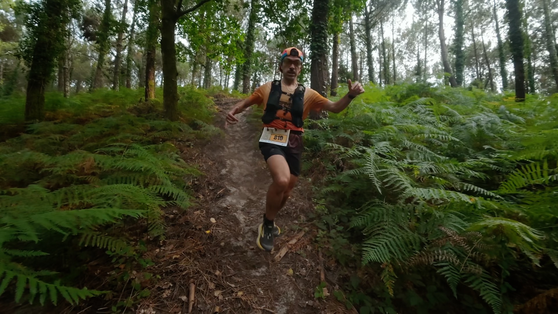 Coureur pouce levé sur le sentier étroit entre fougères