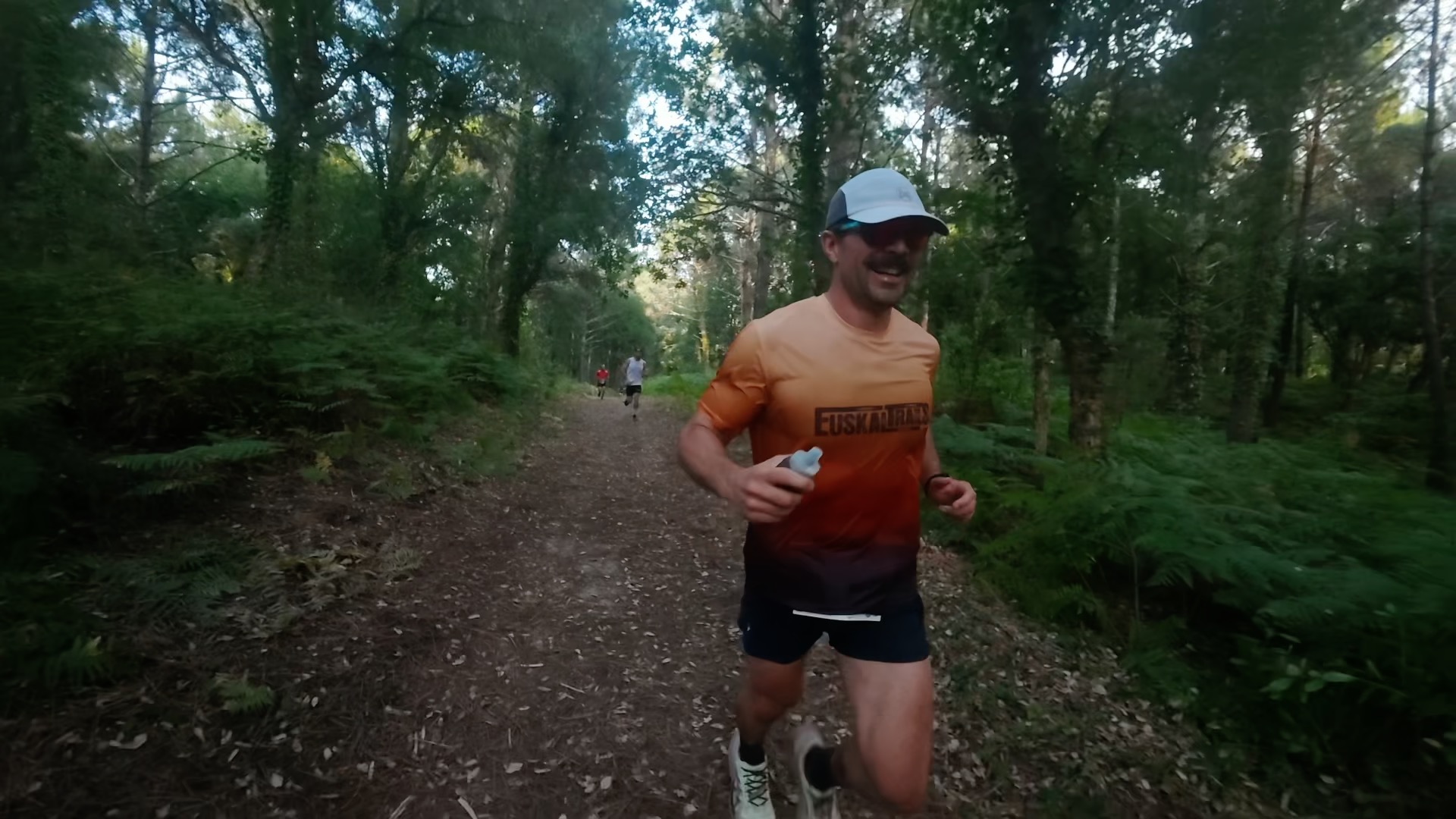 Coureur souriant en t-shirt Euskadi sur sentier en forêt