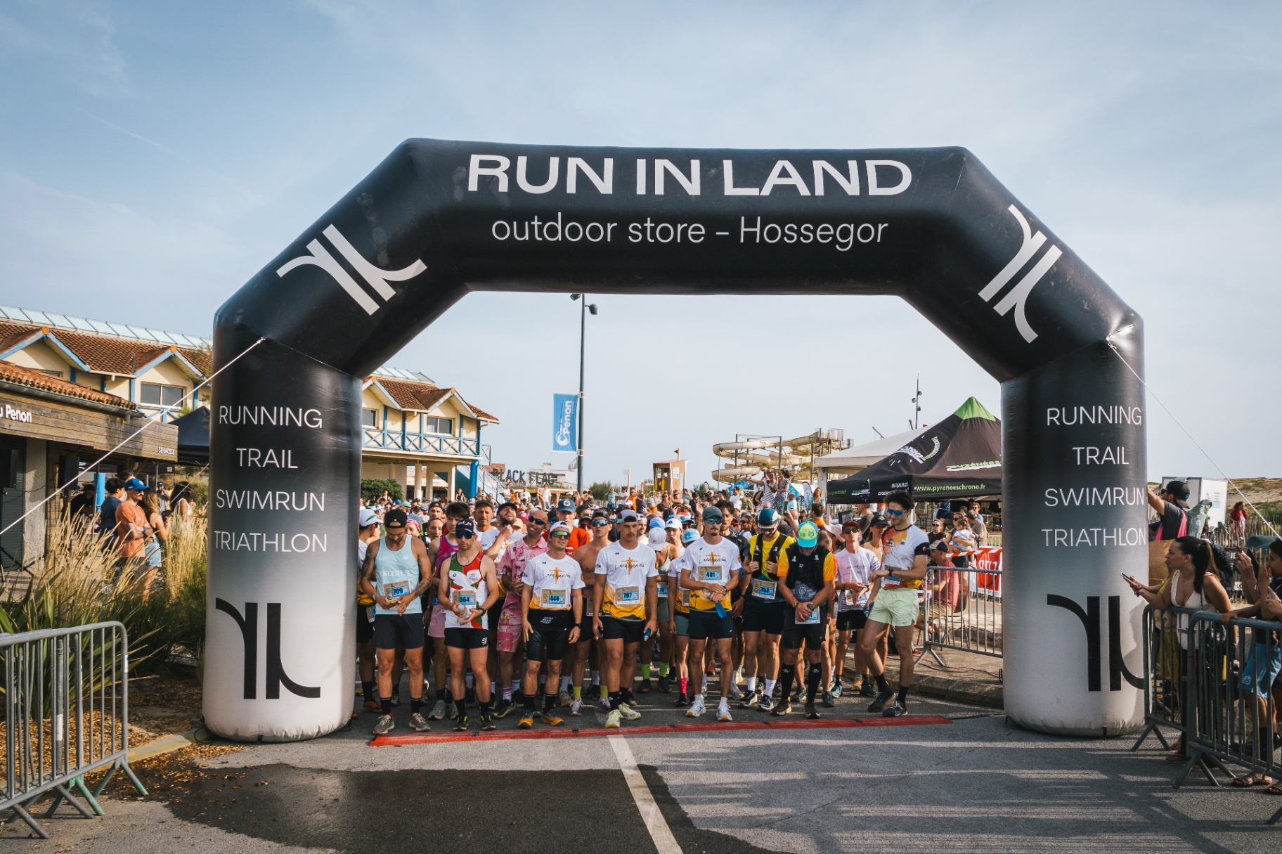 Peloton sous l'arche Run In Land avant le départ au Penon
