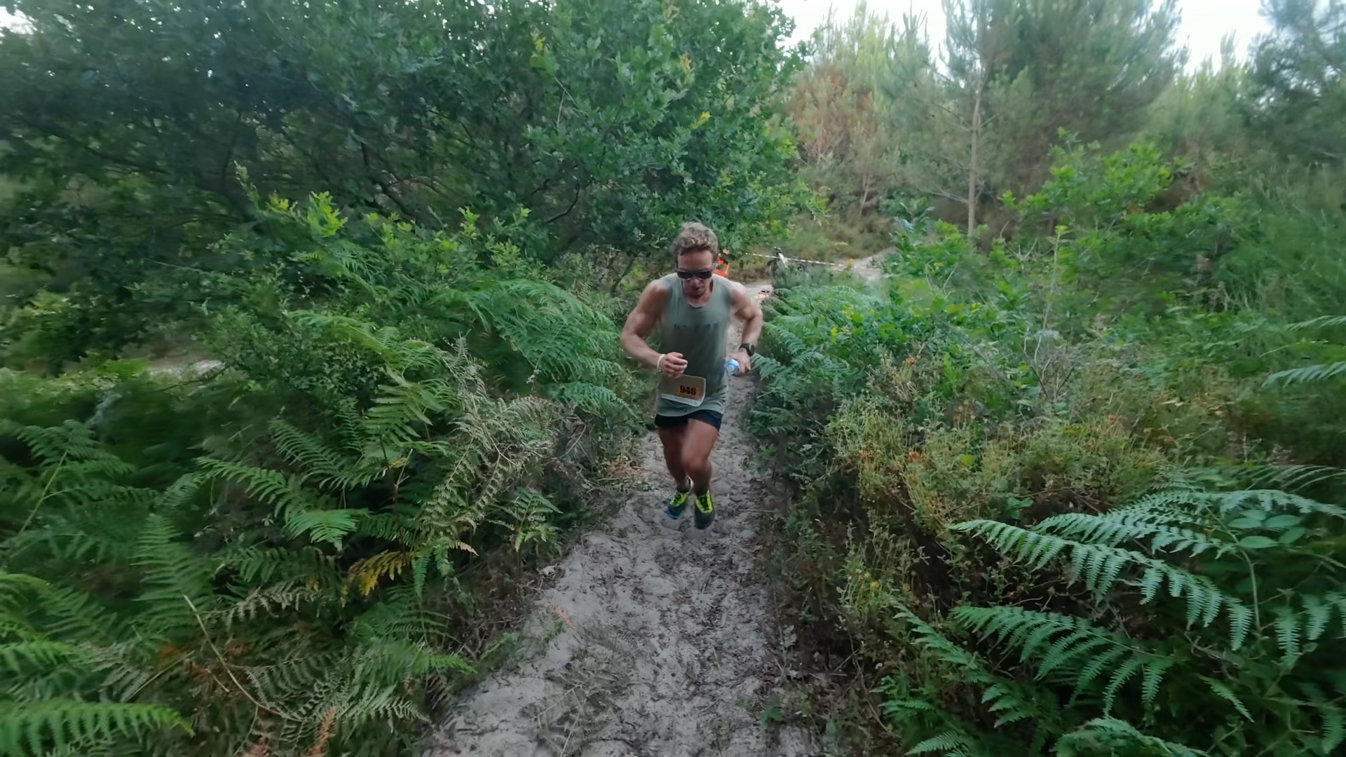 Coureur en montée sur single track sablonneux entre les fougères