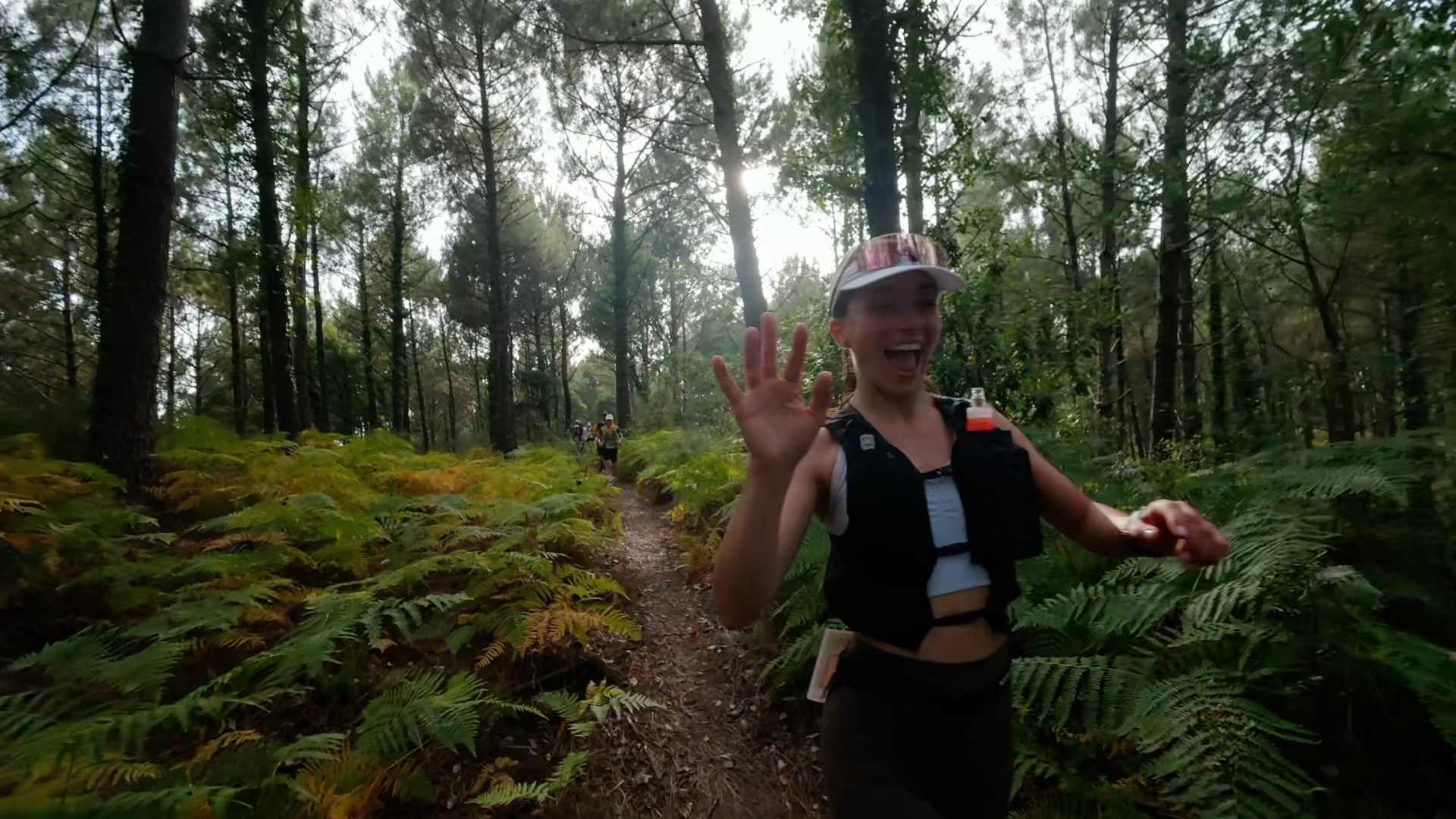 Coureuse en pleine course, main levée entre les fougères