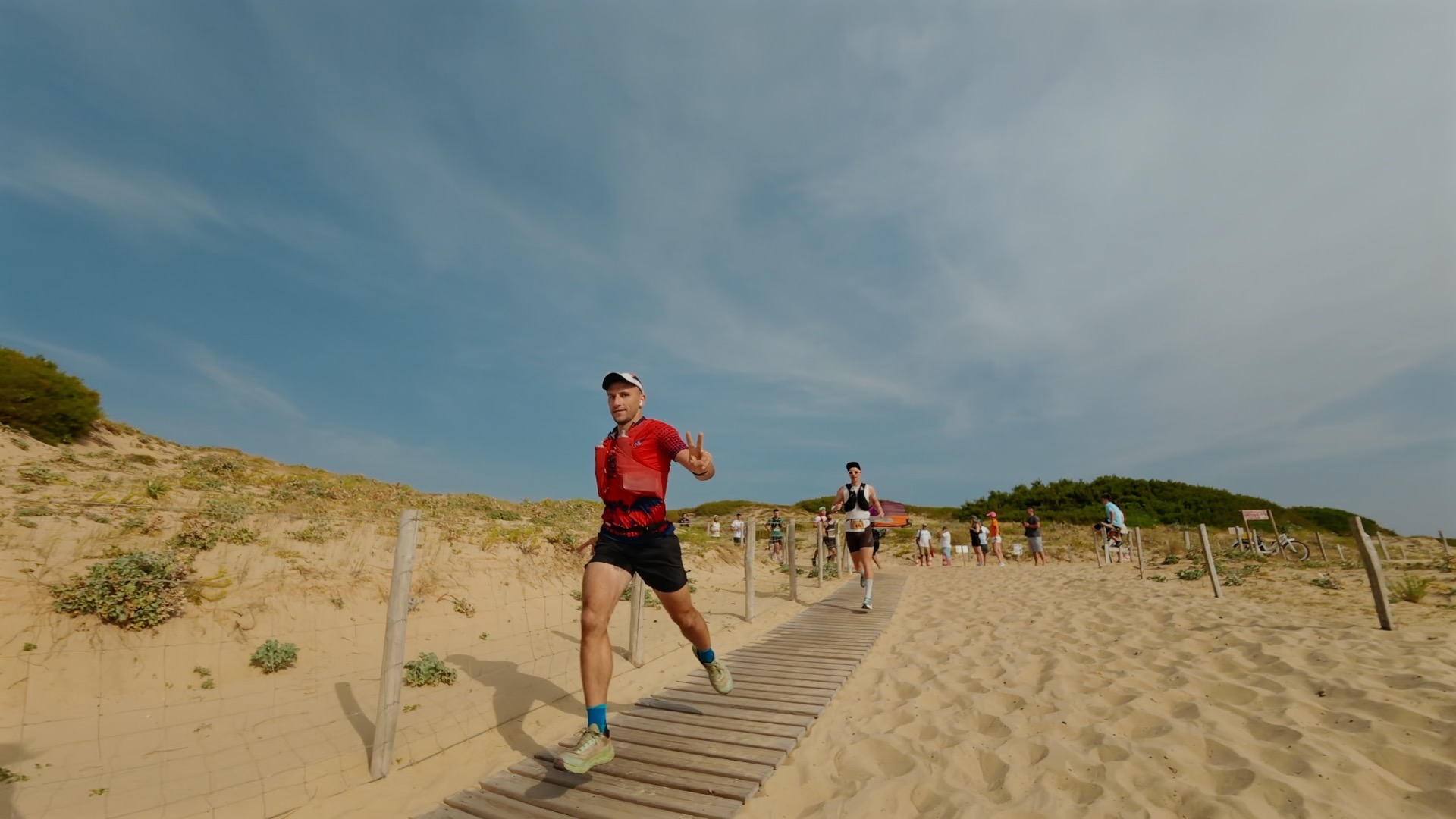 Coureur signe de la victoire sur la passerelle dans la dune