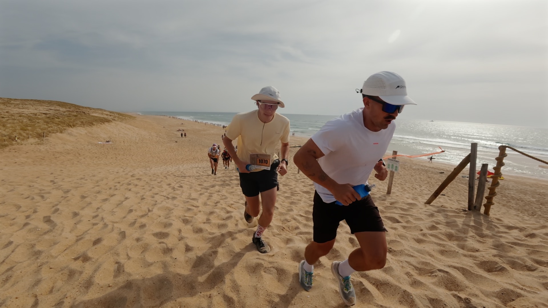 Deux coureurs en montée sur la dune face à l'océan