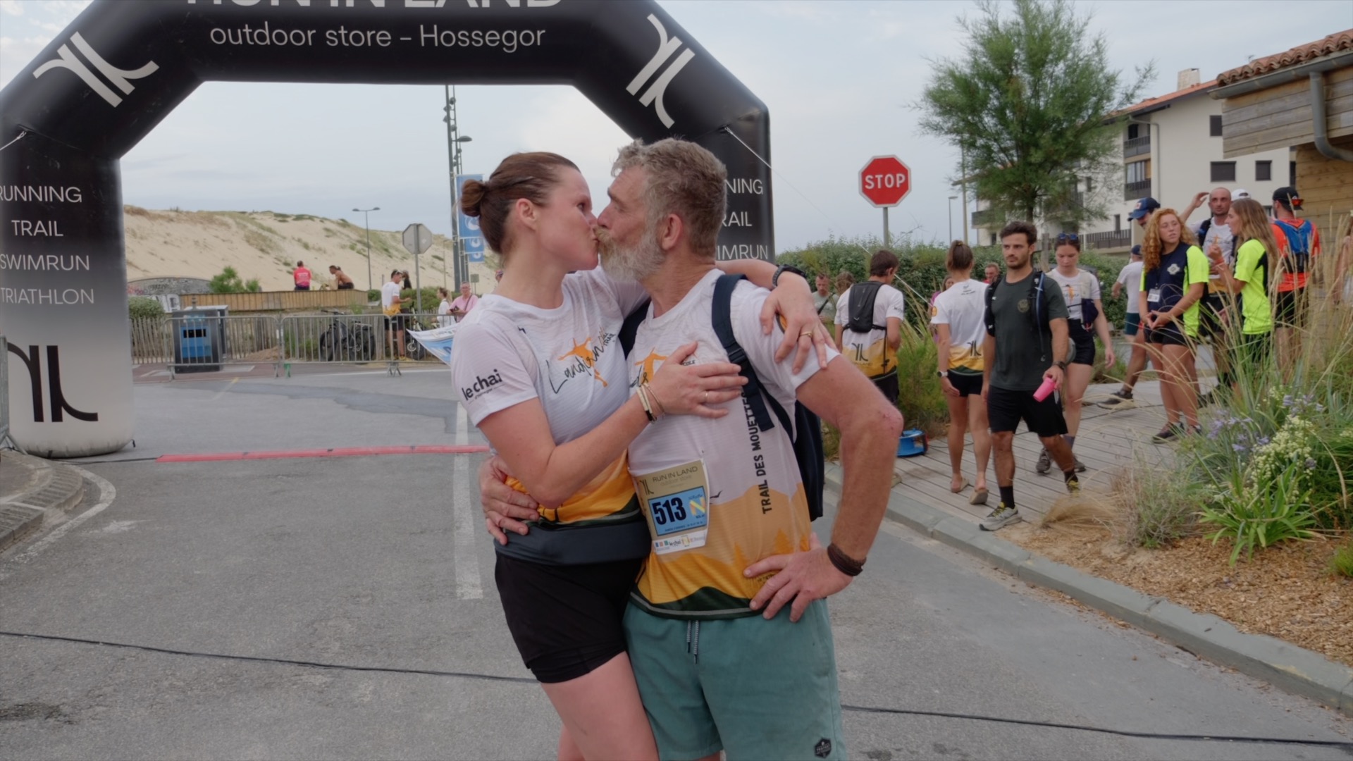 Baiser d'une coureuse à un finisher sous l'arche d'arrivée